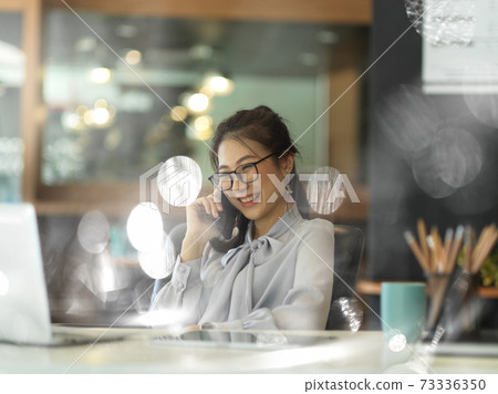 View through glass window of businesswoman talking on the phone View through glass window of businesswoman talking on the phone 73336350