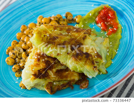 Cabbage leaves in batter with garbanzos and sauce is tasty vegetarian dish 73336447