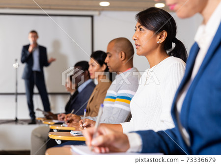 Confident woman listening to lecture at conference 73336679