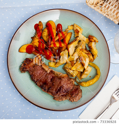 Veal steak with grilled potato and artichokes Veal steak with grilled potato and artichokes 73336928