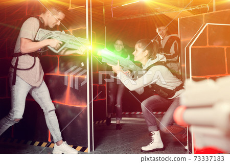 Group of young people playing laser tag game with laser guns 73337183