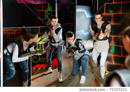 Group of young people playing laser tag game with laser guns Group of young people playing laser tag game with laser guns 73337221