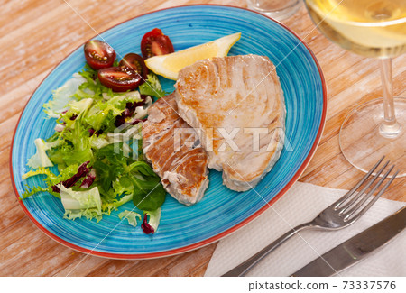 Scandinavian cuisine seafood served with greens and vegetables on plate on wooden table Scandinavian cuisine seafood served with greens and vegetables on plate on wooden table 73337576