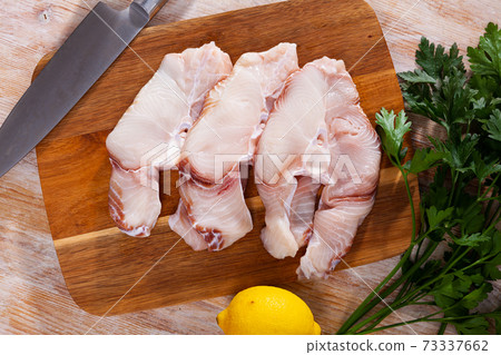 Pieces of fresh blue shark with parsley and lemon on wooden surface Pieces of fresh blue shark with parsley and lemon on wooden surface 73337662