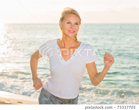 Female in white T-shirt is jogging 73337705