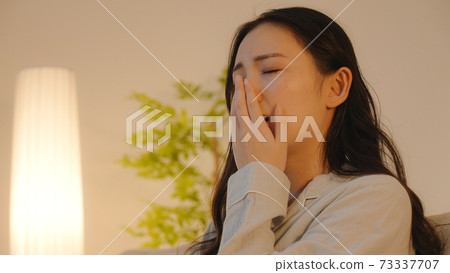 Young woman sitting on the sofa at night 73337707