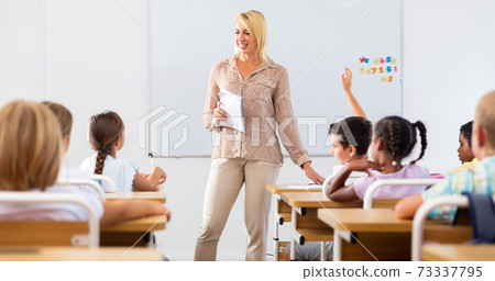 Woman teacher lecturing to pupils at classroom Woman teacher lecturing to pupils at classroom 73337795