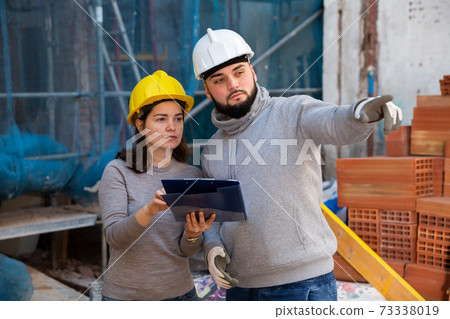 Engineers discussing blueprint at construction site 73338019