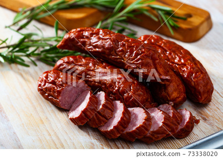 Sliced half-smoked sausages susena on wooden table. Traditional Chezh meat products Sliced half-smoked sausages susena on wooden table. Traditional Chezh meat products 73338020