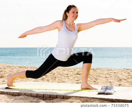 Woman doing yoga standing Woman doing yoga standing 73338075
