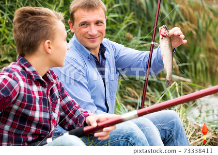 Man with teenager boy showing catch fish Man with teenager boy showing catch fish 73338411