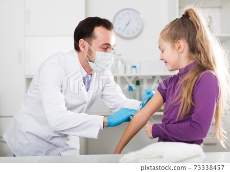 Male doctor injecting little patient 73338457