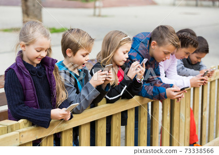 Outdoor portrait of girls and boys playing with phones Outdoor portrait of girls and boys playing with phones 73338566