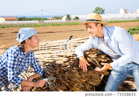 Man and woman farmers breezily chatting in vegetable garden Man and woman farmers breezily chatting in vegetable garden 73338633
