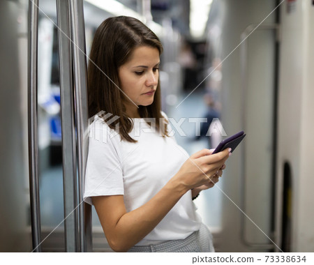 Female using tablet in subway wagon 73338634