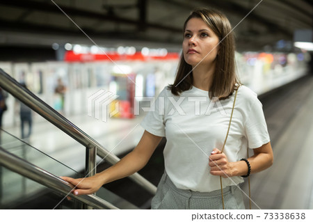 Woman on subway station escalator 73338638