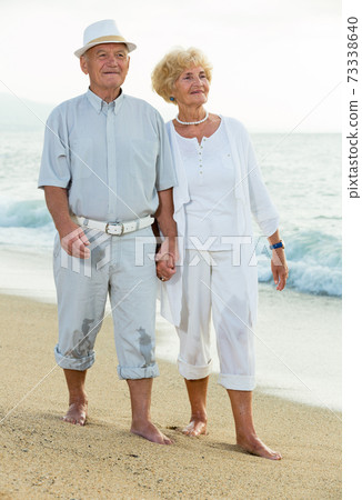 cheerful pensioners walking barefoot together cheerful pensioners walking barefoot together 73338640