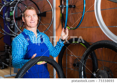 Man seller in uniform picking new bicycle wheel hands 73338693