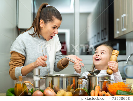 Emotional mother and little daughter tasting soup together Emotional mother and little daughter tasting soup together 73338698