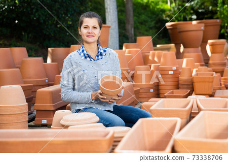 Woman chooses pots clay pots in store warehouse Woman chooses pots clay pots in store warehouse 73338706