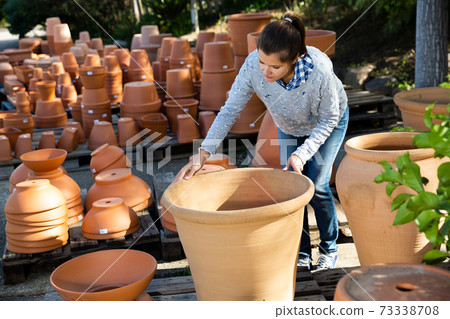 Woman choosing big pot for plants Woman choosing big pot for plants 73338708