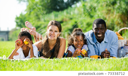 Couple with children lying on green lawn Couple with children lying on green lawn 73338712