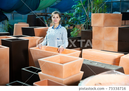 Woman choosing big pot for plants 73338716