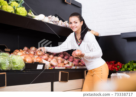 Young glad woman choosing onions Young glad woman choosing onions 73338717