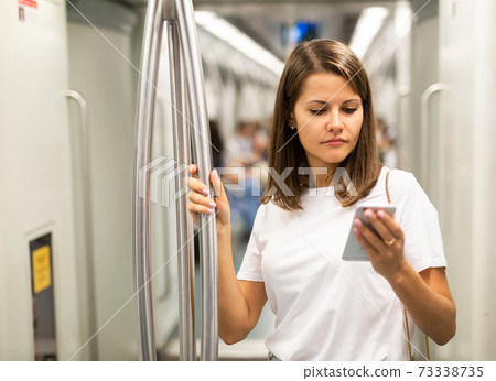 Woman using phone in subway car 73338735