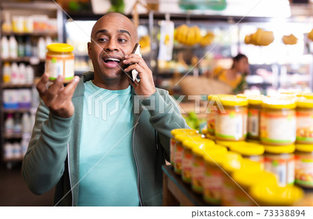 Smiling Latin American talking on phone at grocery store Smiling Latin American talking on phone at grocery store 73338894