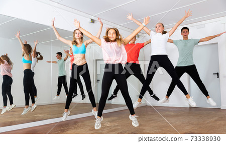 Teenagers with teacher jumping in dance hall 73338930