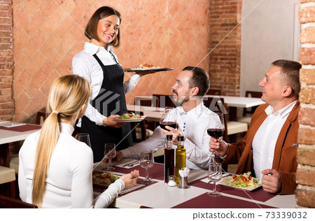 Waitress placing order in front of guests Waitress placing order in front of guests 73339032