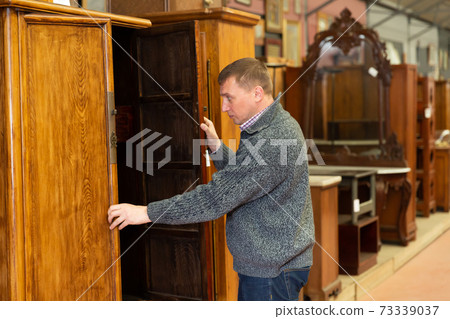 Buyer choosing wooden furniture in salon Buyer choosing wooden furniture in salon 73339037