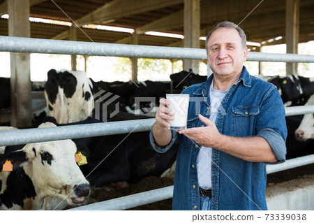 Male farm owner with milk on dairy farm 73339038