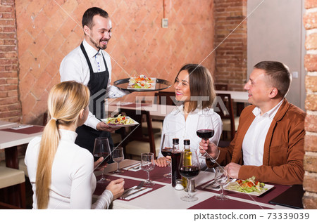 Ordinary male waiter carrying order for visitors 73339039