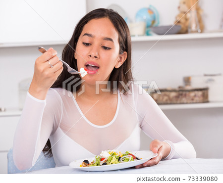 Positive young female eating salad Positive young female eating salad 73339080