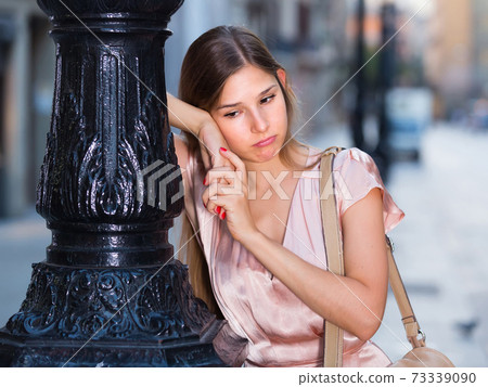 sad girl standing outside in city 73339090