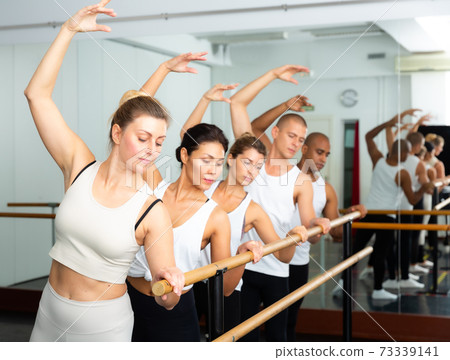 Ballet dancers stands near the ballet barre at ballet hall. 73339141