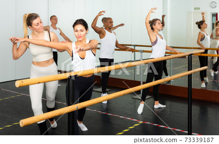 Ballet dancer woman training four multiethnic people in bright fitness room 73339187