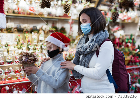 Tween boy with mother in protective masks on Christmas street market Tween boy with mother in protective masks on Christmas street market 73339230