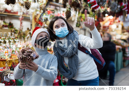 Preteen boy and his mother in protective masks at Christmas fair Preteen boy and his mother in protective masks at Christmas fair 73339254