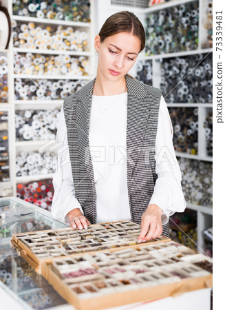 Woman choosing buttons in shop Woman choosing buttons in shop 73339481