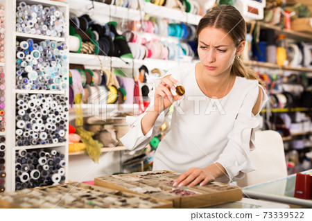 Woman choosing buttons in shop Woman choosing buttons in shop 73339522