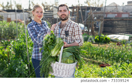 Couple holding baskets of harvest Couple holding baskets of harvest 73339524