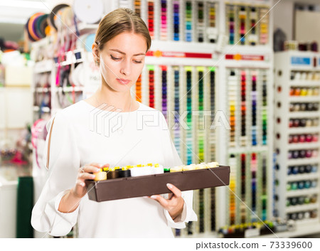 Woman looking for threads in haberdasher shop Woman looking for threads in haberdasher shop 73339600
