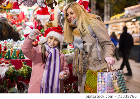 Happy mom and daughter choose christmas balls at street market Happy mom and daughter choose christmas balls at street market 73339766
