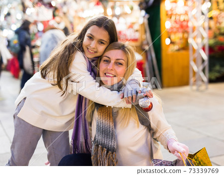 Portrait of happy family after shopping for gifts - daughter hugs mom at market 73339769