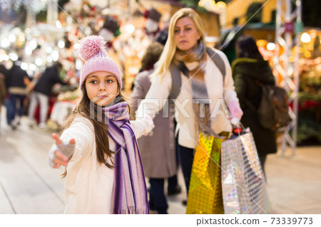 Daughter asks mom to buy Christmas present at market Daughter asks mom to buy Christmas present at market 73339773