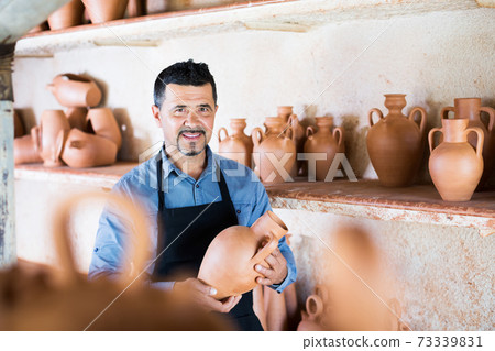 Craftsman with ceramic crockery 73339831