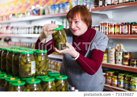 female choosing canned jar of cucumbers female choosing canned jar of cucumbers 73339887
